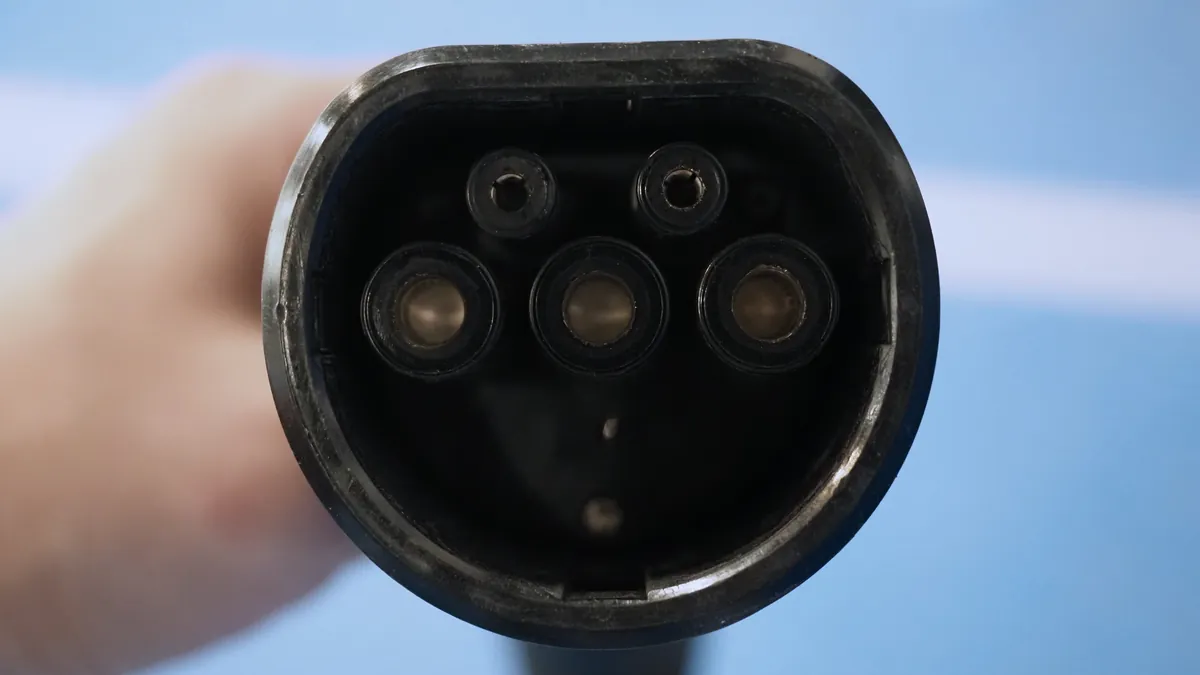 Conector Tipo 2 de un cargador de coche eléctrico revisado en mano