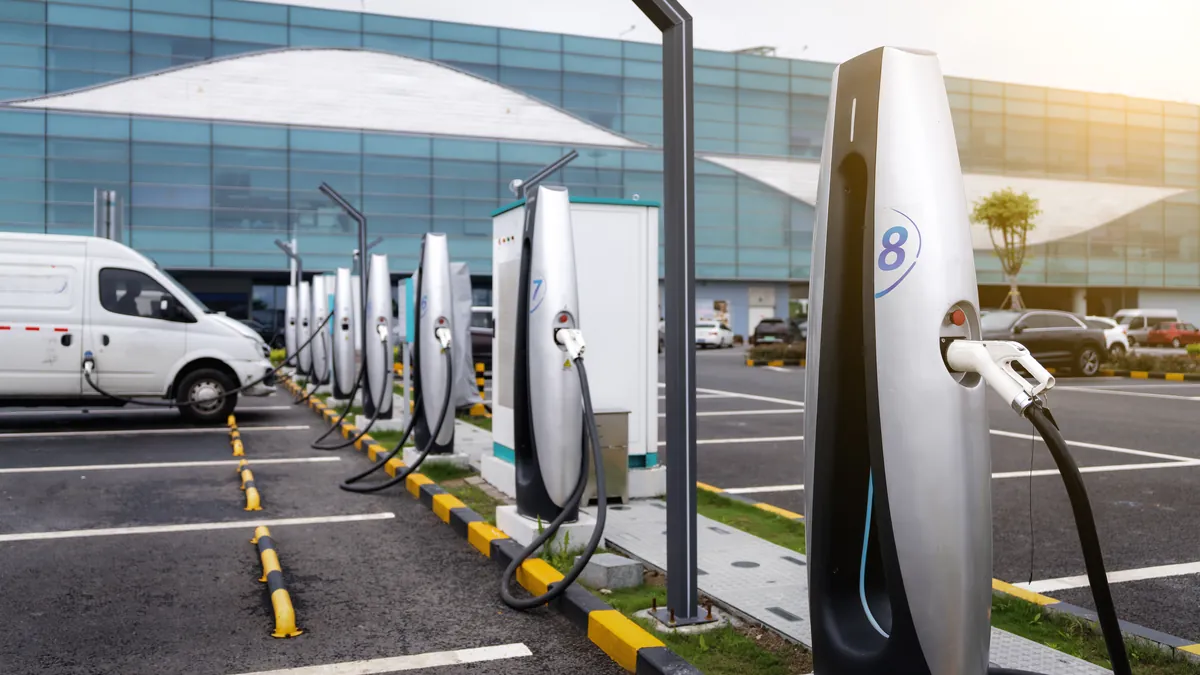 Furgonetas y coches eléctricos de empresa cargando en una fila de puntos de recarga
